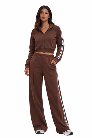 Woman wearing a brown tracksuit with white stripes on a white background