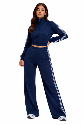 Woman wearing a navy tracksuit with white stripes on a white background